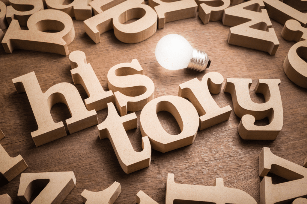 The word 'history' is spelled out in wooden letters with a lightbulb nearby